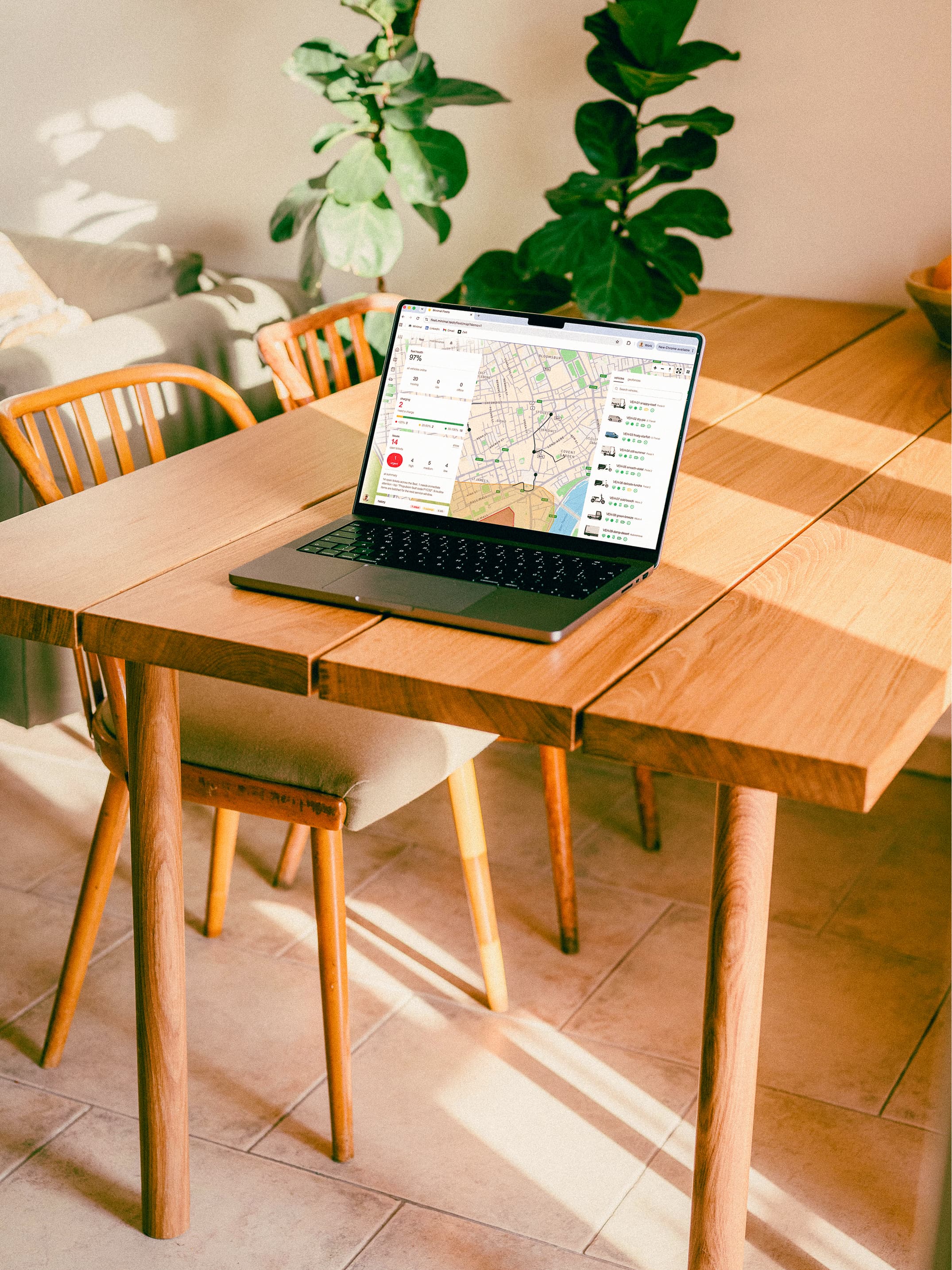 A laptop on a wooden table showing the FleetOS fleet-management map